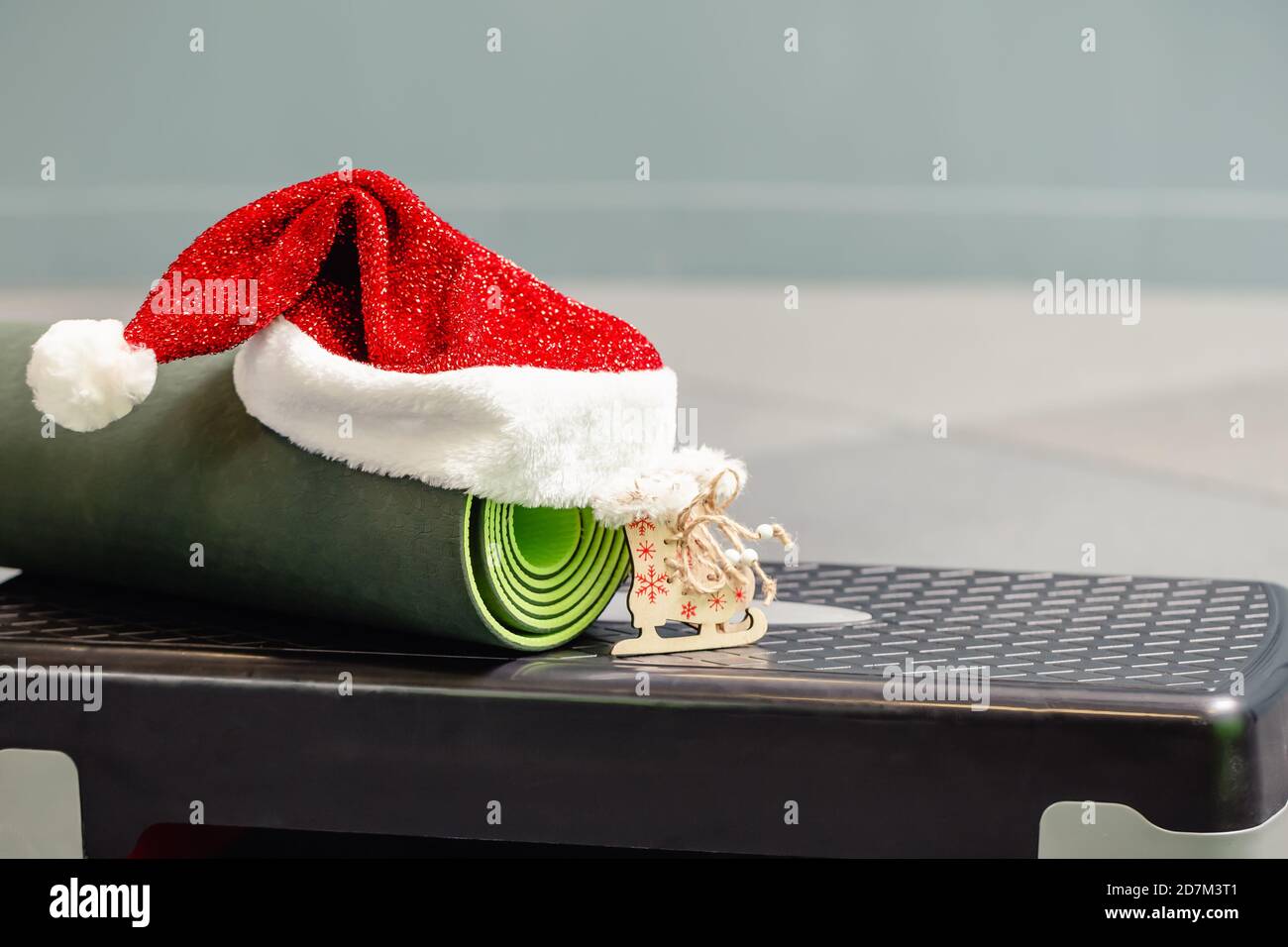 Primo piano di tappetino grigio con cappello Babbo Natale in palestra. Miglior regalo di Natale per una persona attiva. Concetto di yoga xmas. Foto Stock