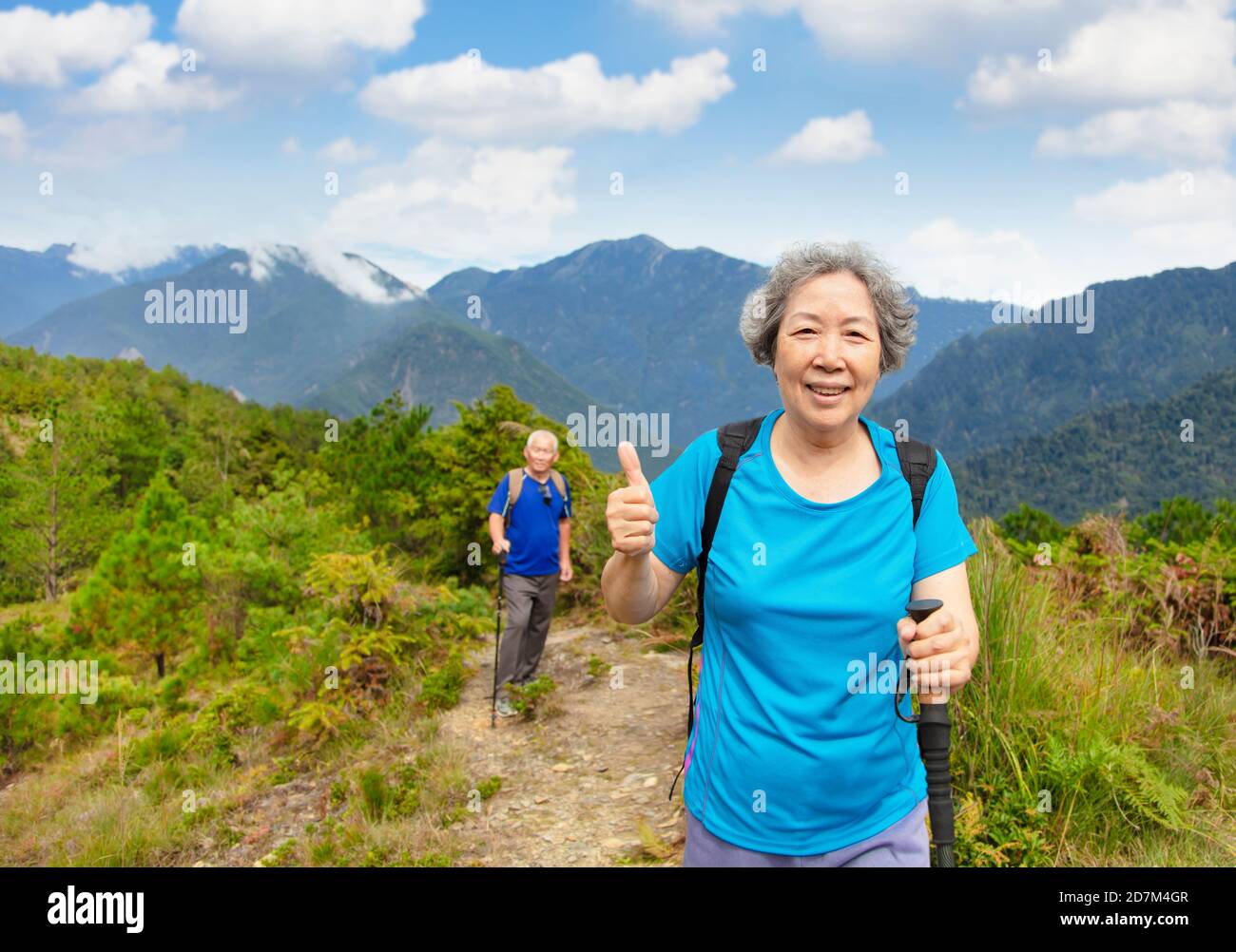 Happy Senior coppia trekking sulla montagna e mostrando pollice su Foto Stock