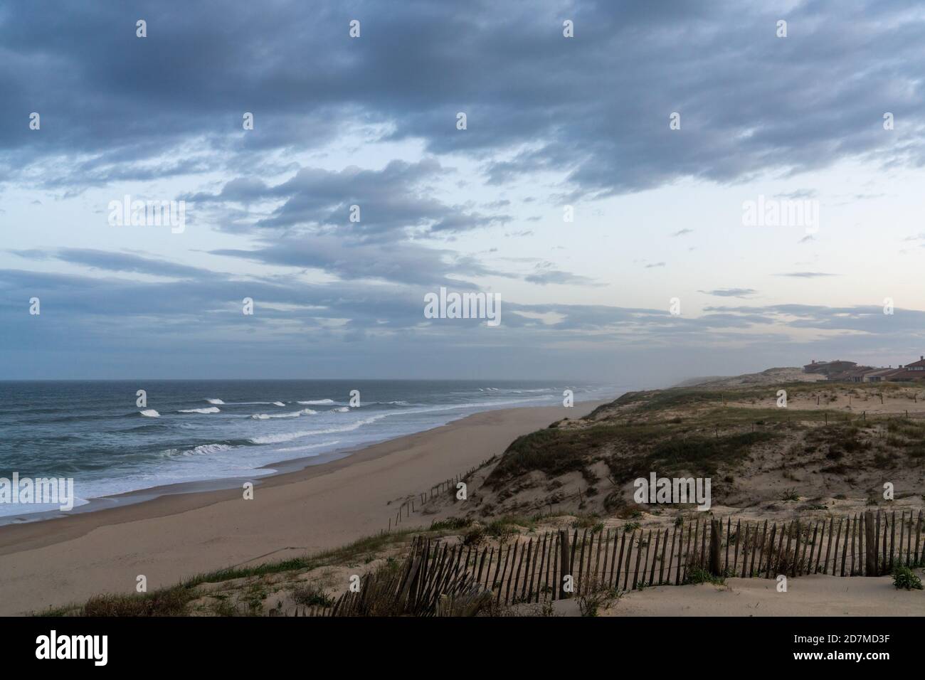 dune di sabbia e onde che si infrangono su una spiaggia infinita sotto Un cielo tempestoso in Francia Foto Stock