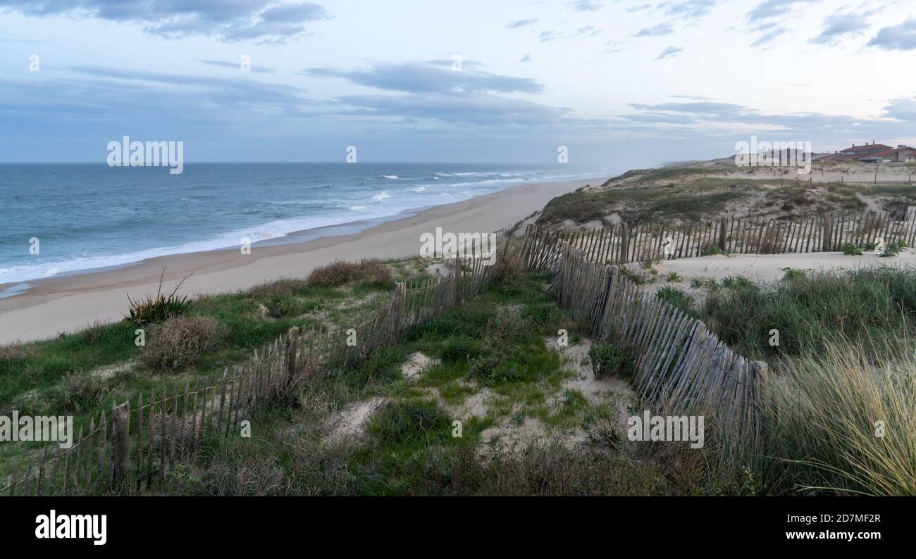 dune di sabbia e onde che si infrangono su una spiaggia infinita sotto Un cielo tempestoso in Francia Foto Stock