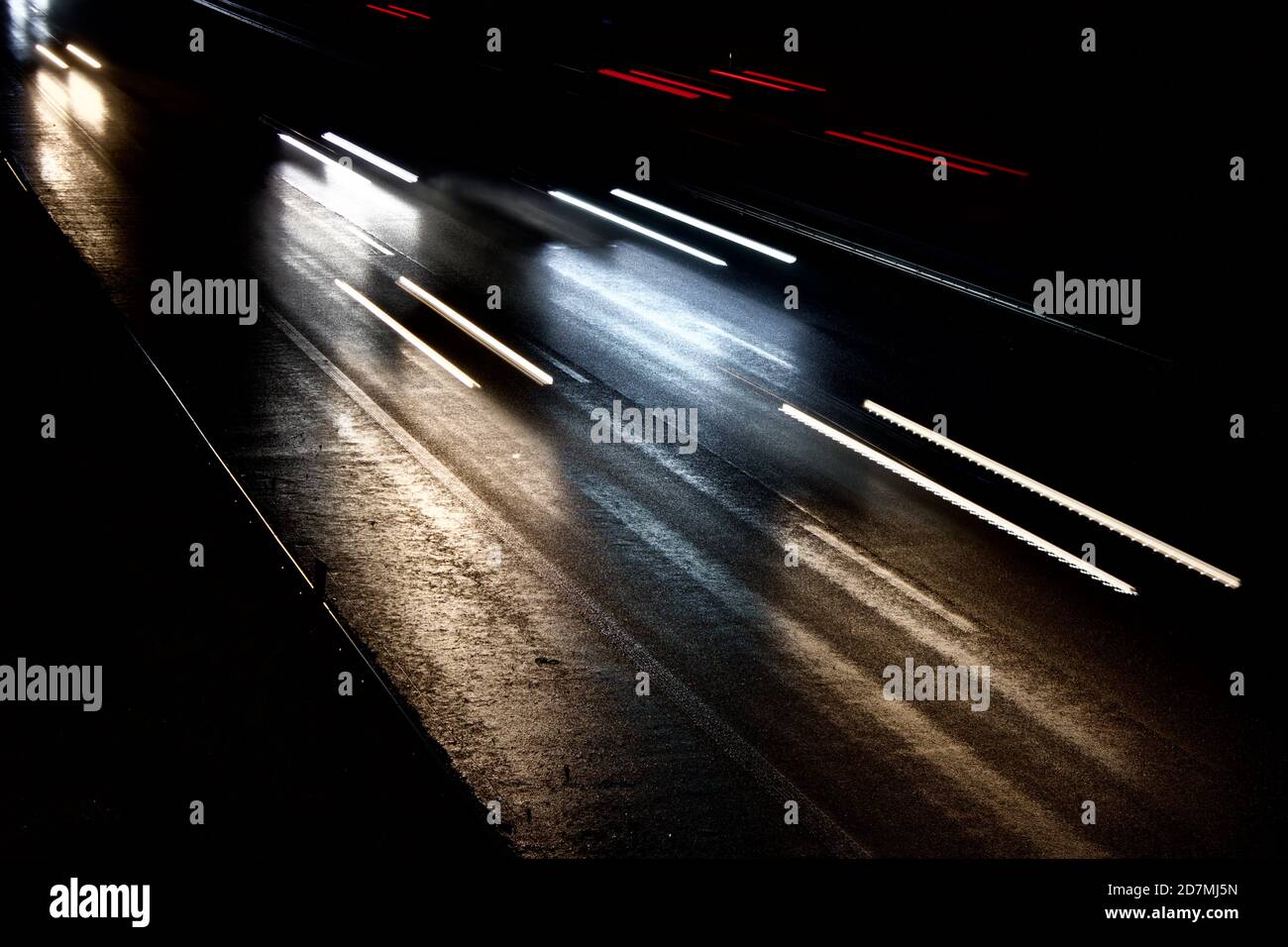 le auto si muovono velocemente su un'autostrada buia e umida Foto Stock