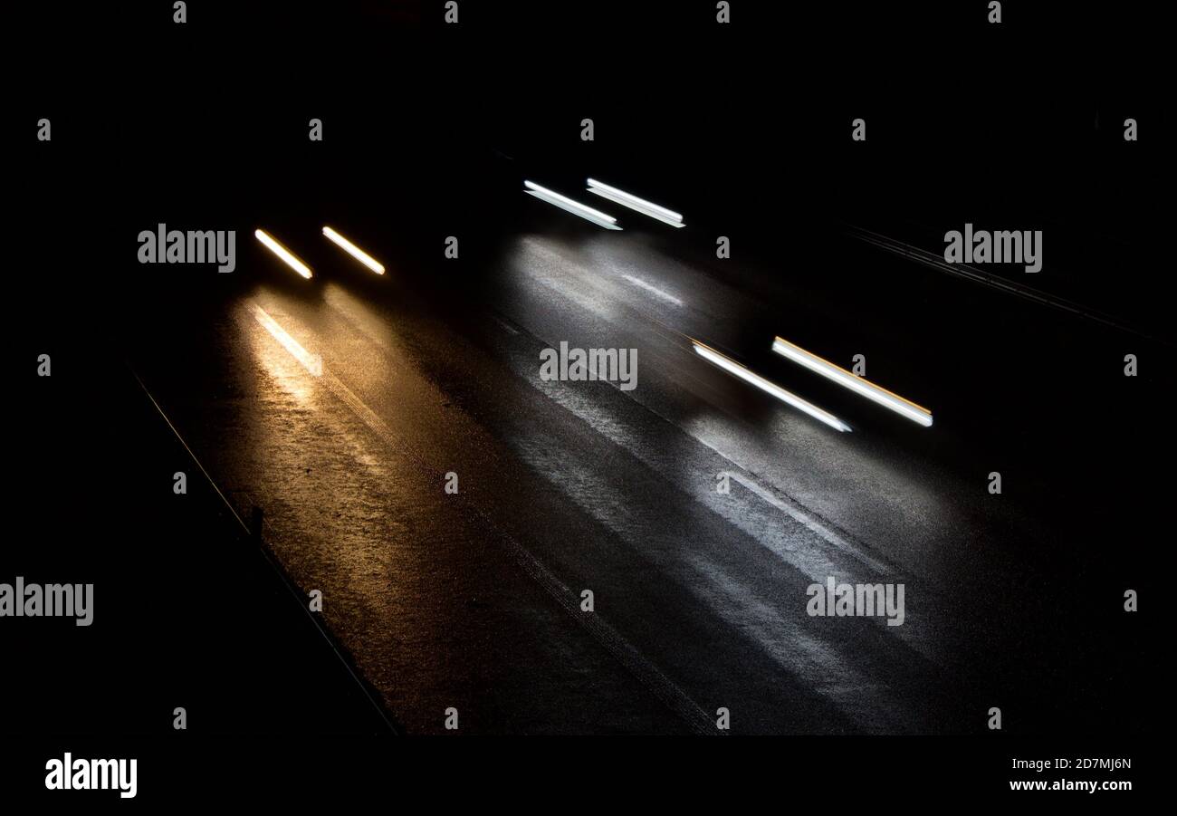 le auto si muovono velocemente su un'autostrada buia e umida Foto Stock