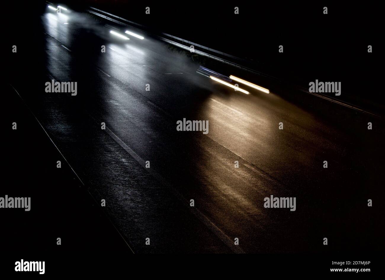 le auto si muovono velocemente su un'autostrada buia e umida Foto Stock
