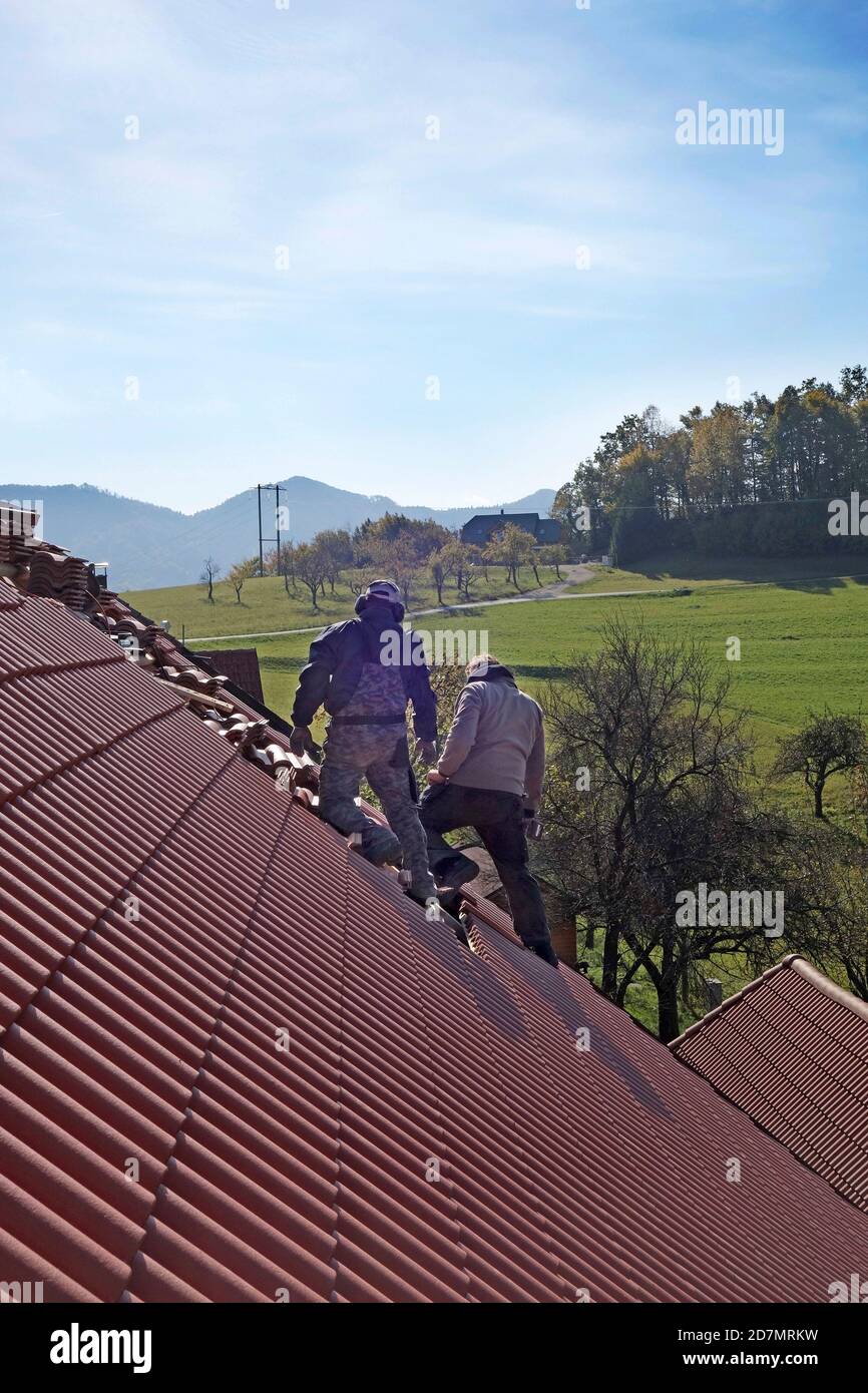 Appaltatori del tetto che posano le nuove piastrelle su un fienile. Foto Stock