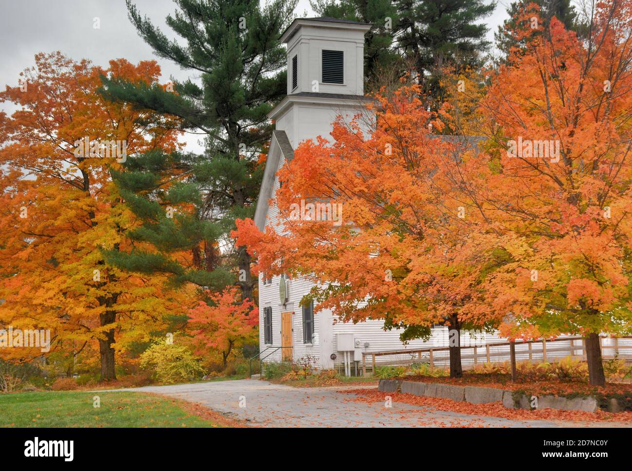 Autunno nella panoramica New England. Alberi di acero giallo e arancio brillanti che incorniciano la storica sala riunioni della città nel rurale Wilton Center, New Hampshire. Foto Stock