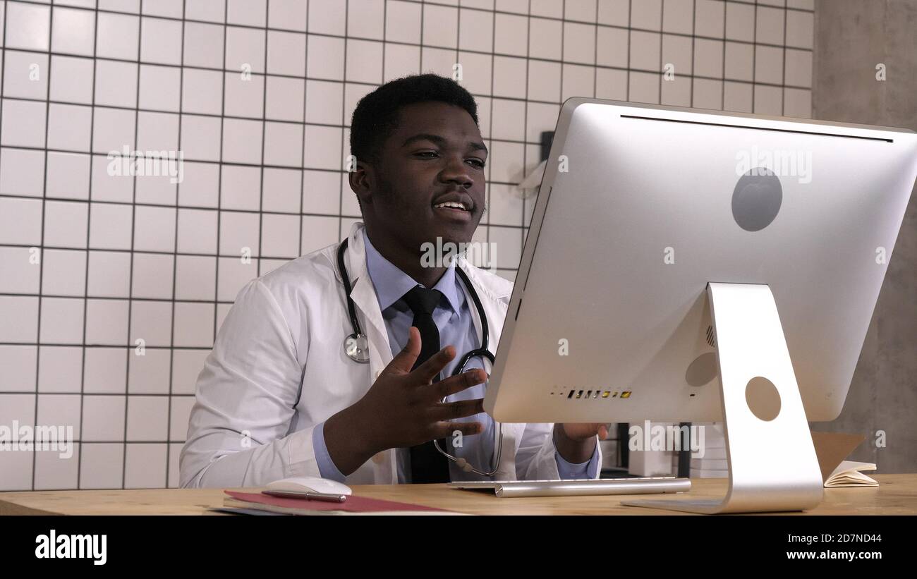 Maschio africano medico avente conferenza video sul suo computer. Foto Stock