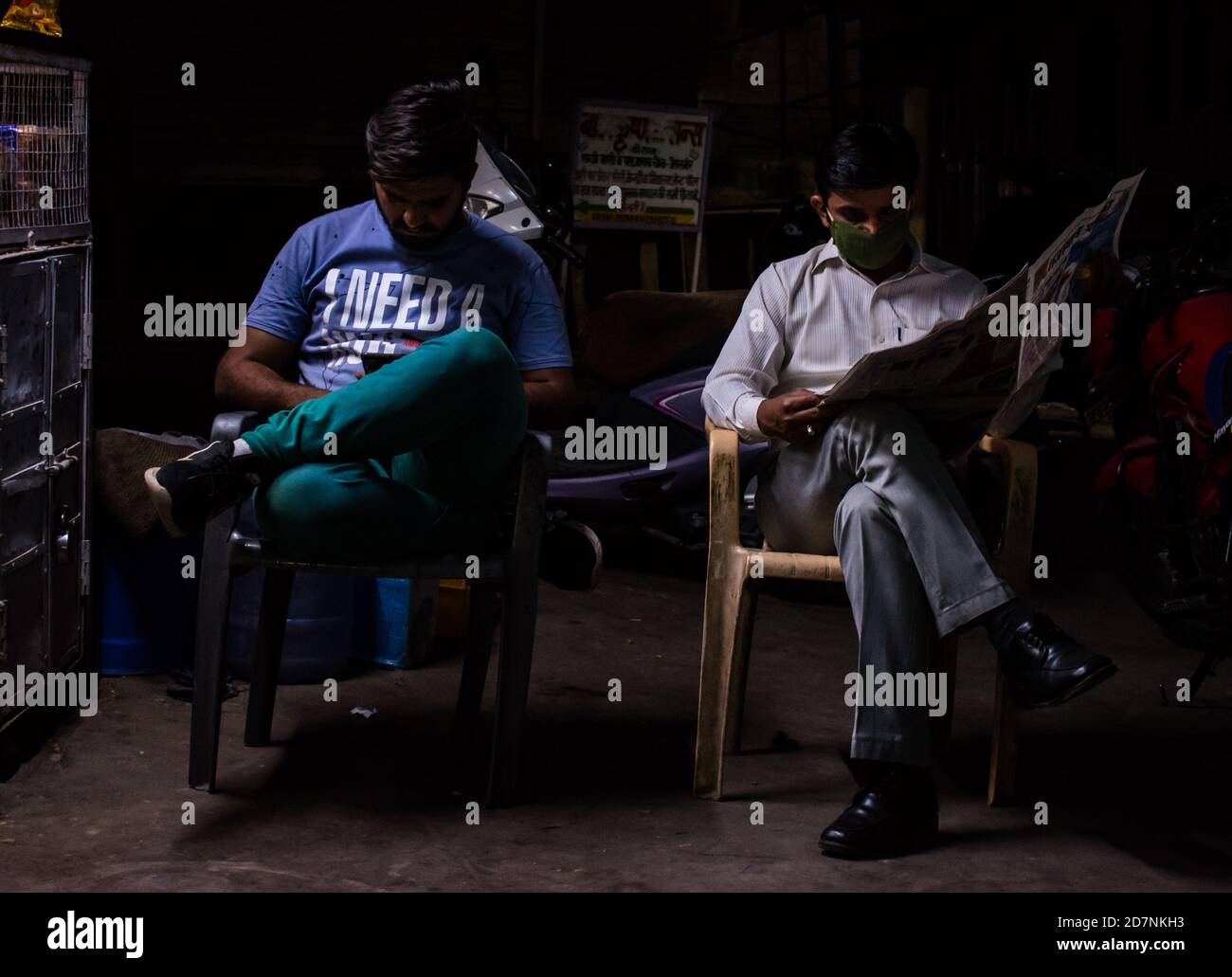 Jaisalmer, Rajasthan / India - settembre 24 2020 : Padre e figlio che leggono il giornale e che usano il telefono di notte mostra il divario di generazione Foto Stock