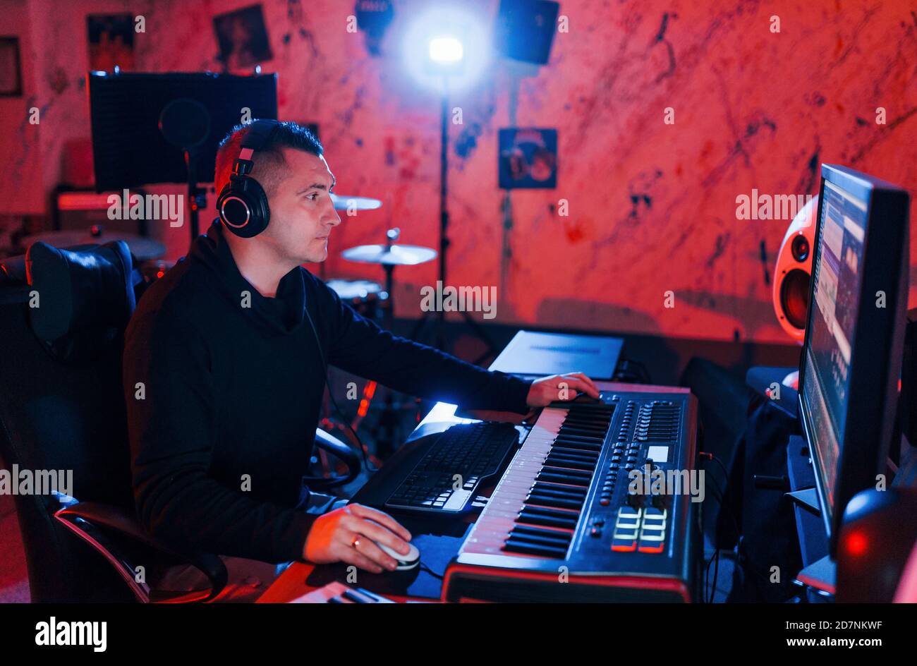 Un giovane tecnico di suono che lavora e mescola musica all'interno del studio Foto Stock