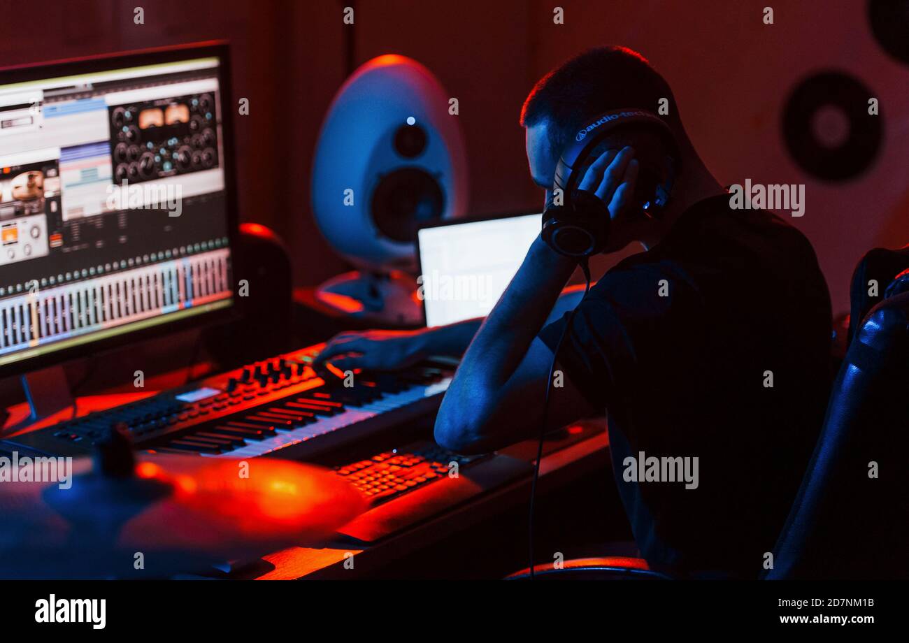 Un giovane tecnico di suono che lavora e mescola musica all'interno del studio Foto Stock