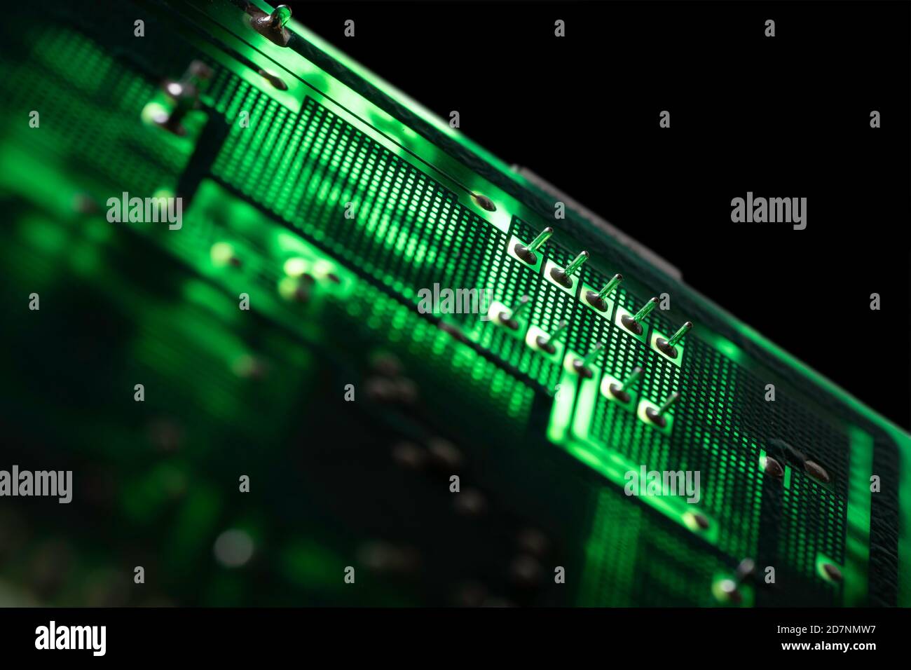 Scheda elettronica verde illuminata con molti componenti elettrici e collegamenti. Immagine futura isolata su sfondo nero Foto Stock