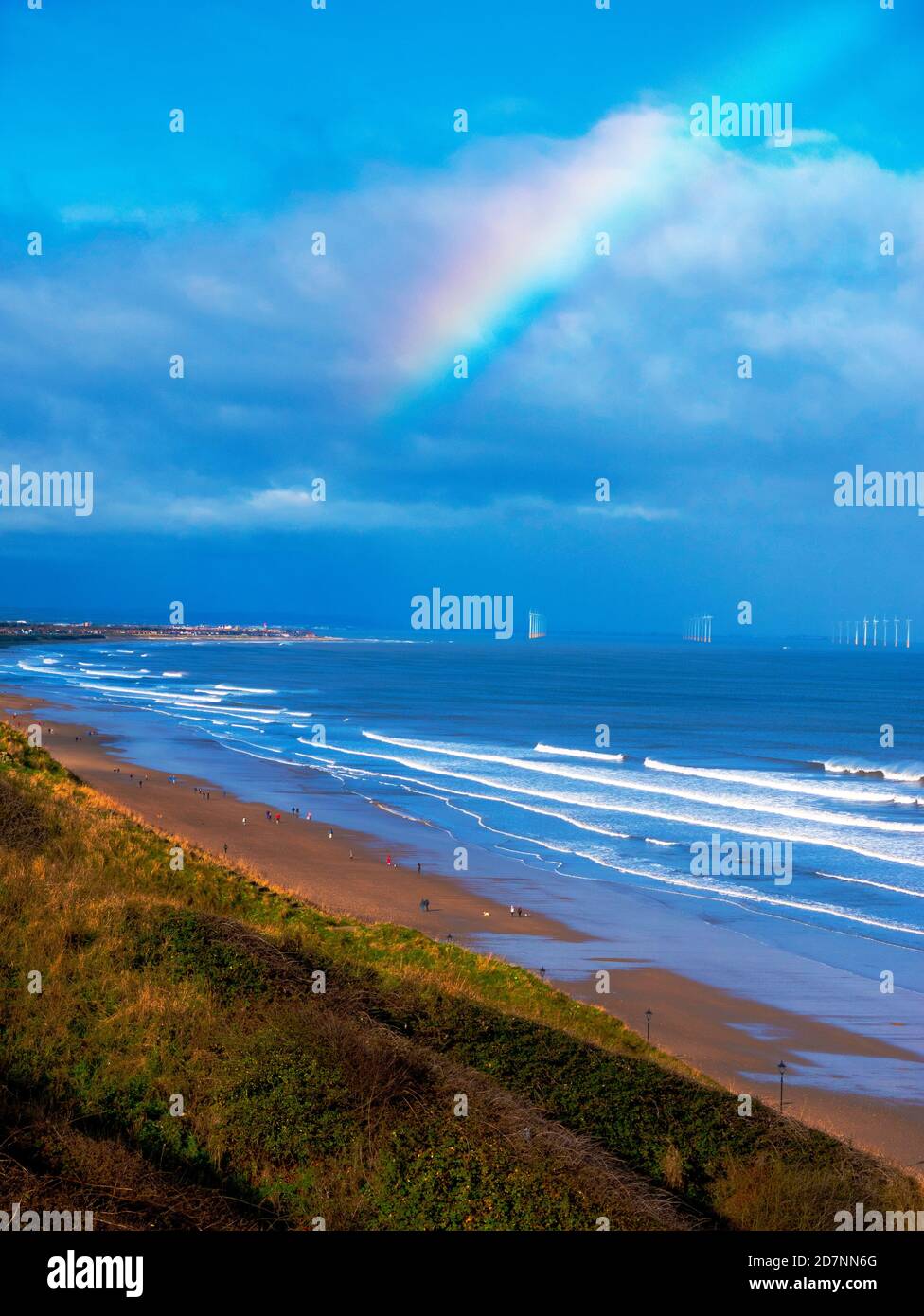 Vista sulla spiaggia di Saltburn che guarda verso Redcar al sole d'autunno cielo blu con un arcobaleno e una vista distante di Un Windfarm offshore Foto Stock