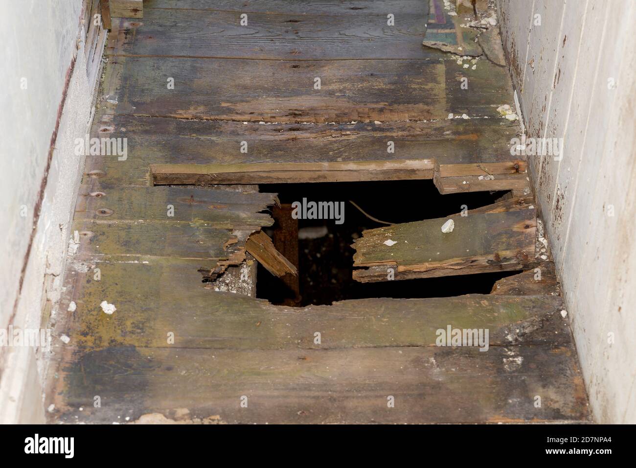 Un buco nel pavimento di un vecchio edificio. Il pavimento è in un  corridoio stretto. Un seminterrato scuro può essere visto attraverso il  foro Foto stock - Alamy