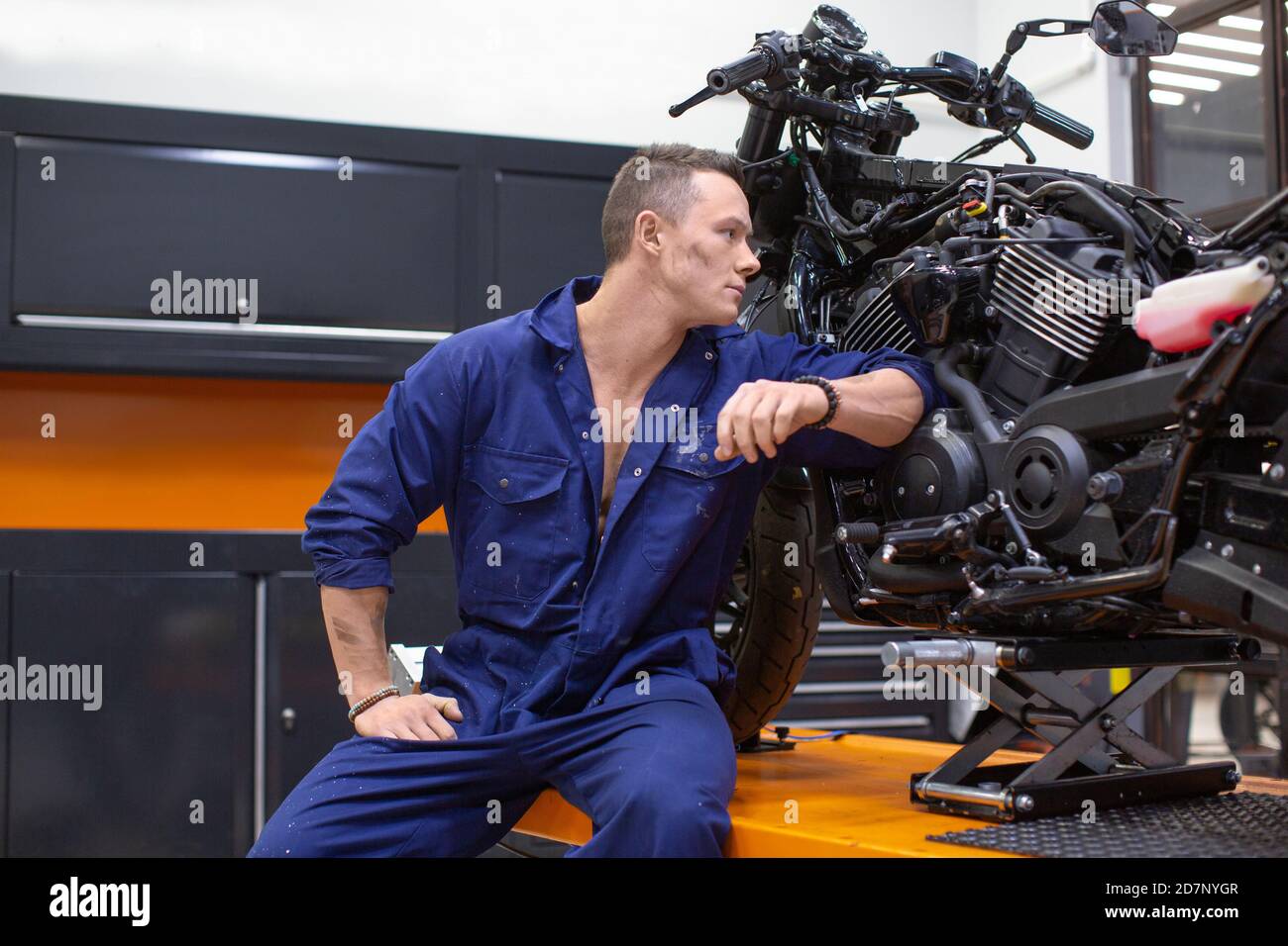 Un uomo in un'officina vicino alla motocicletta Foto Stock