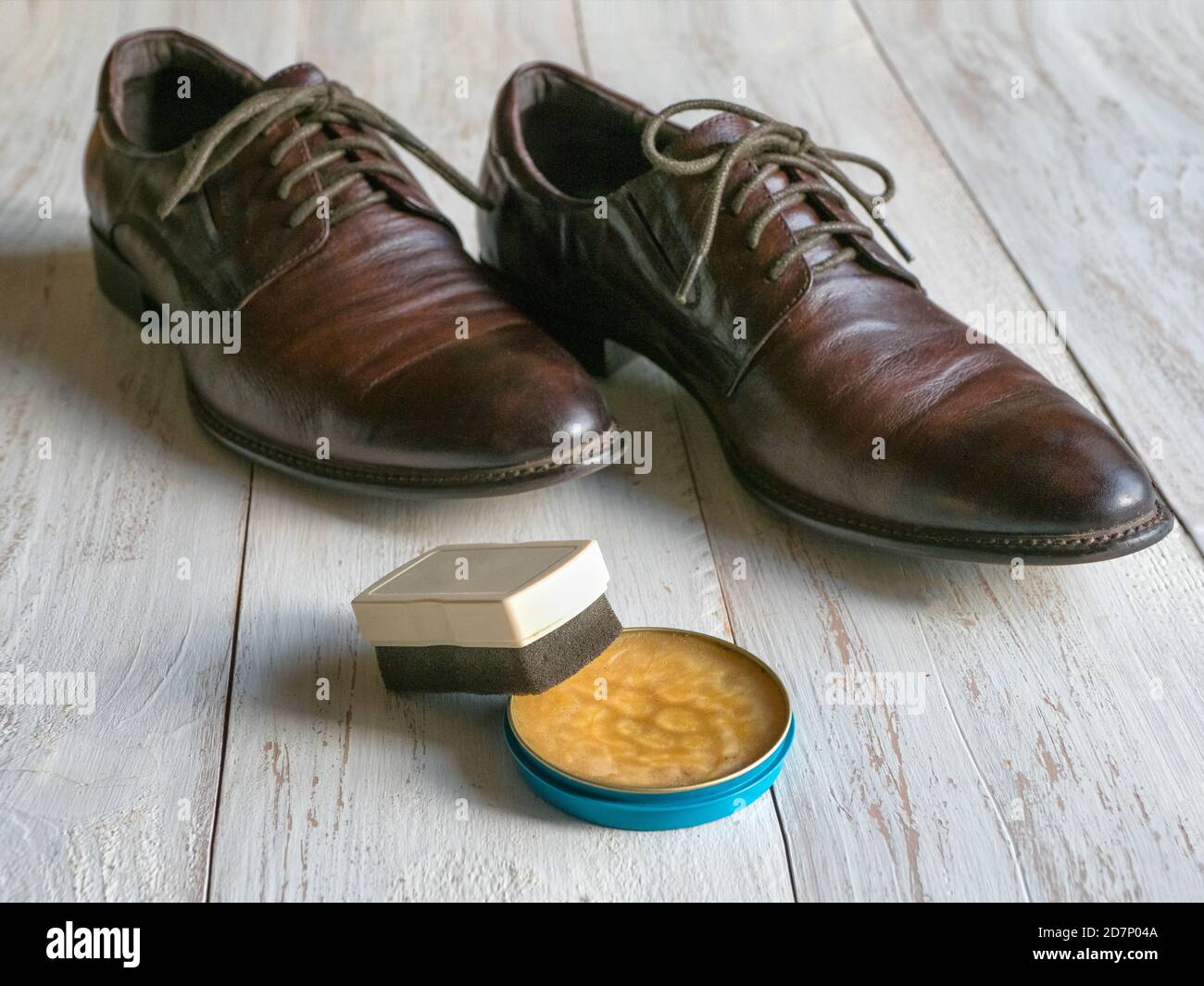 Cera protettiva per scarpe in pelle. Concetto di cura delle scarpe. Un paio di stivali classici sul pavimento in legno. Foto Stock