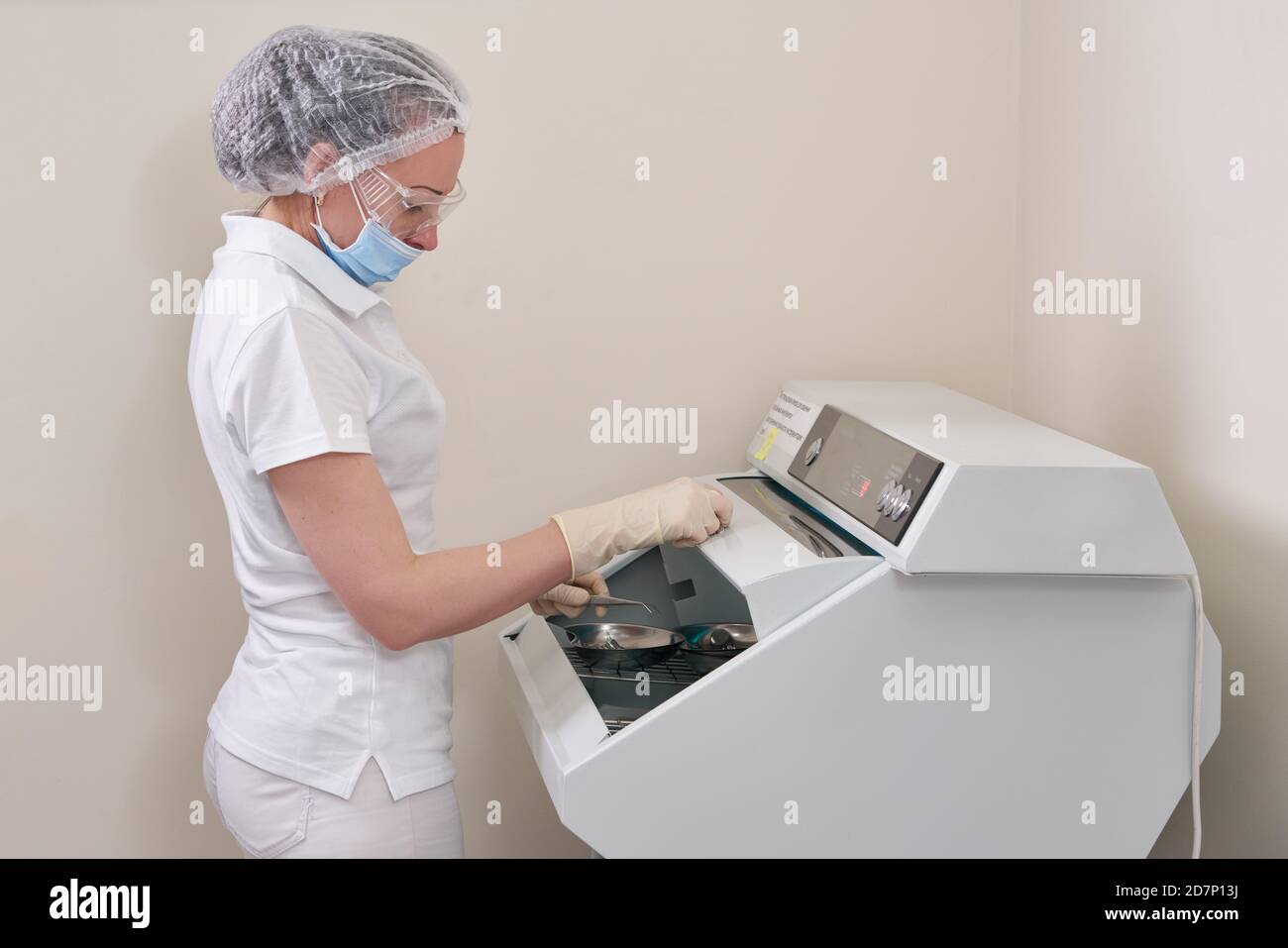 Infermiere femmina che esegue la sterilizzazione di strumenti odontoiatrici in autoclave Foto Stock
