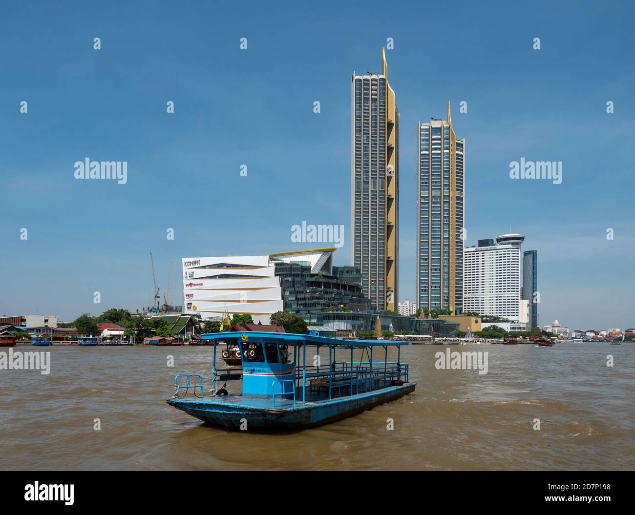 Fiume Chao Praya a Bangkok con un traghetto di traversata sul fiume in primo piano e l'icona del centro commerciale Siam e le torri di residenza sul fiume. Infurt Foto Stock