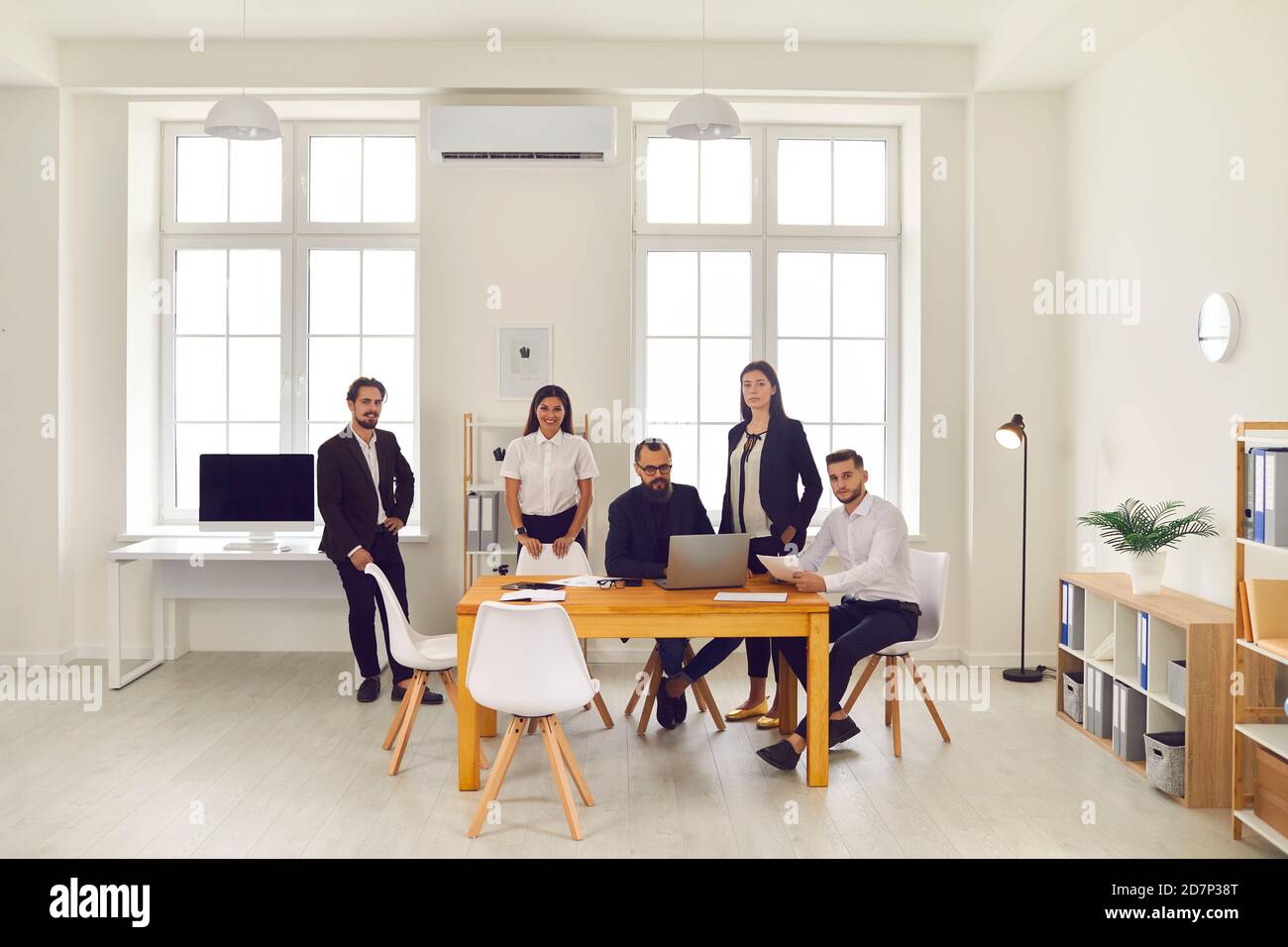 Team di persone che discutono di idee aziendali e sorridono alla telecamera in ufficio. Foto Stock