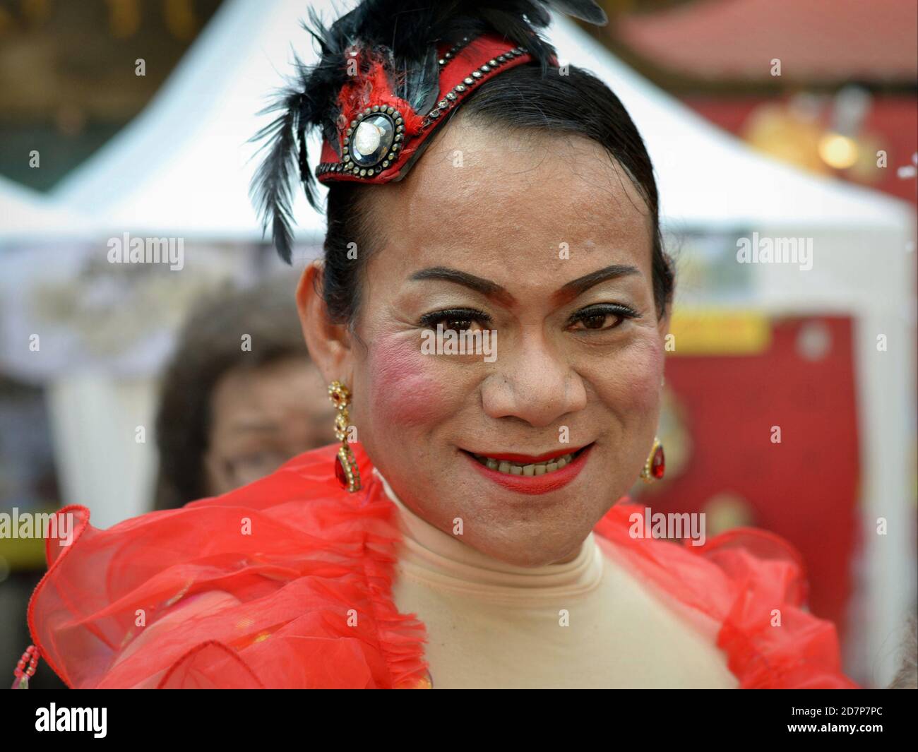 Medio invecchiato vestito thailandese cross-dressing genere queer (kathoey) sorride per la macchina fotografica a Chinatown durante il Capodanno cinese. Foto Stock