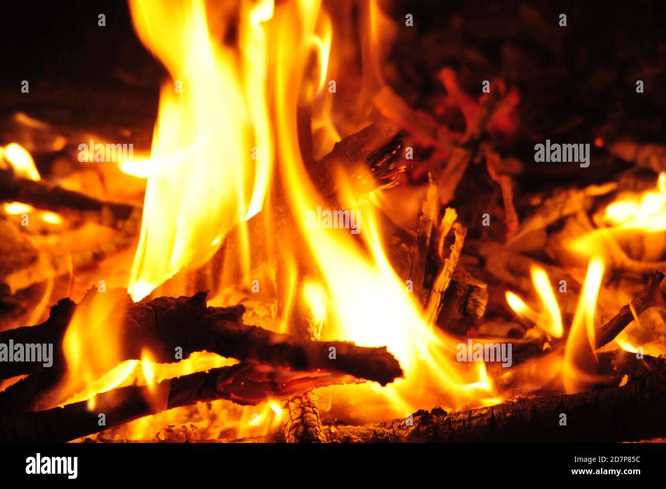fiamme e bagliore in un falò di notte, bruciando bastoni di legno Foto Stock