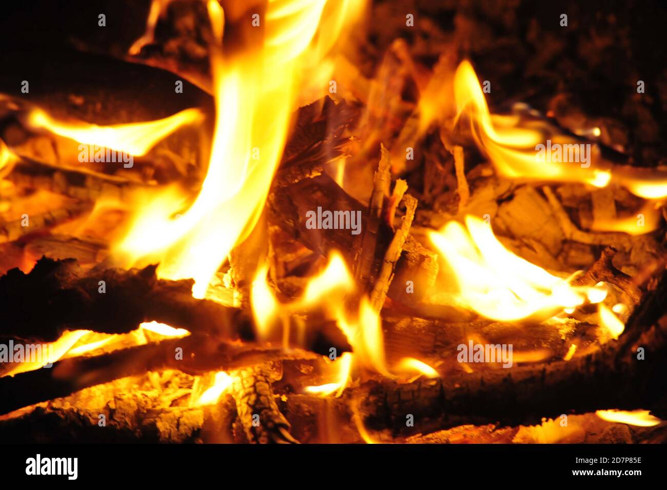 fiamme e bagliore in un falò di notte, bruciando bastoni di legno Foto Stock