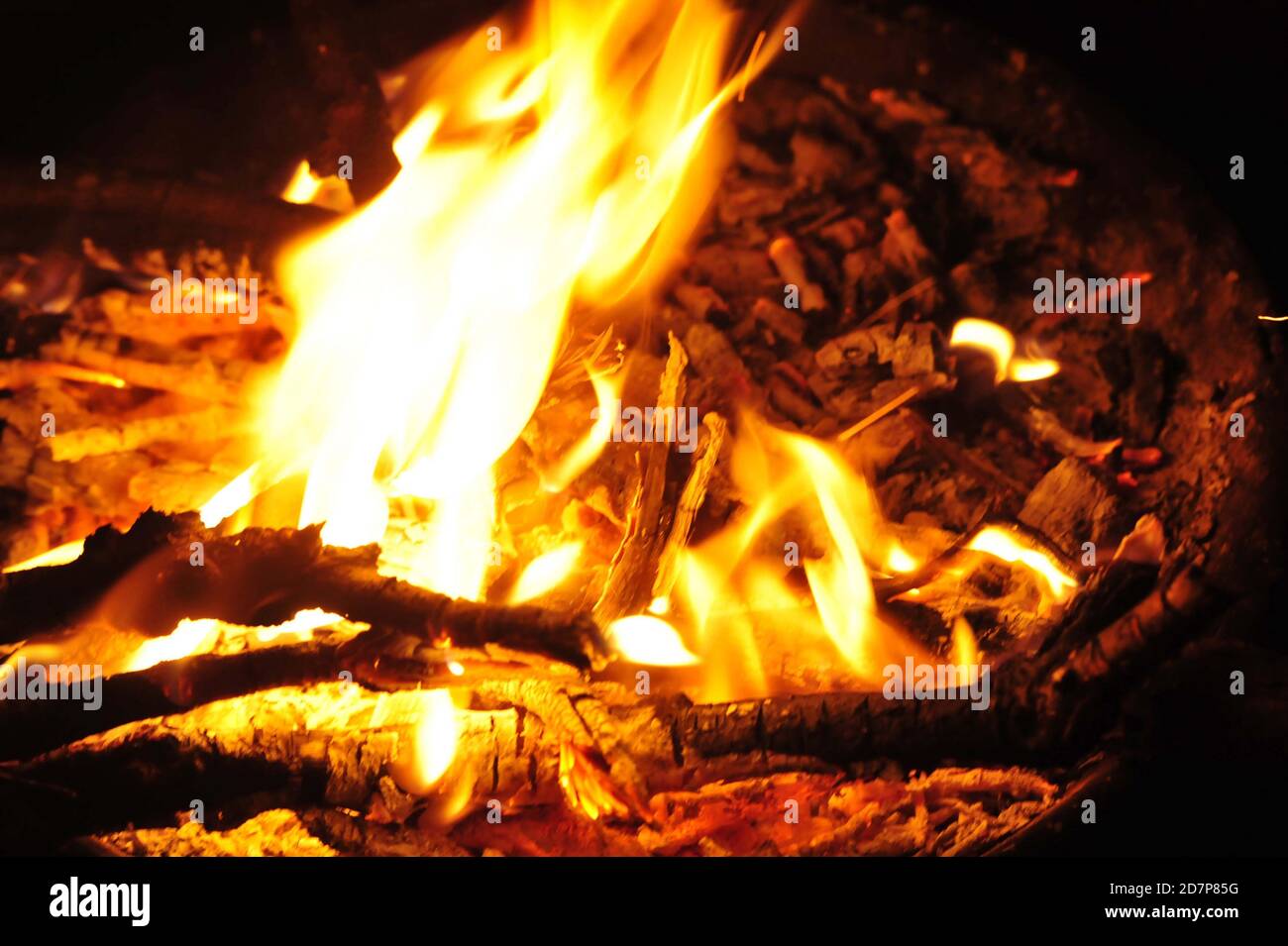 fiamme e bagliore in un falò di notte, bruciando bastoni di legno Foto Stock