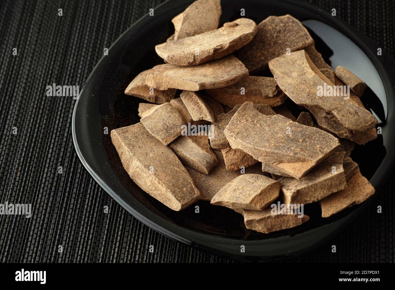 Pasta di cacao in una piastra nera. Theobroma cacao. Tasto basso. Foto Stock