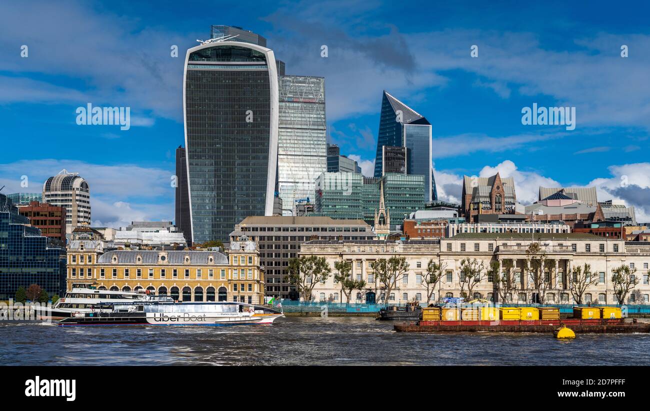 Vista della città di Londra sul fiume - la chiatta dei rifiuti e il River Bus di marca UBER passano davanti all'edificio Walkie Talkie e al quartiere finanziario della città di Londra. Foto Stock