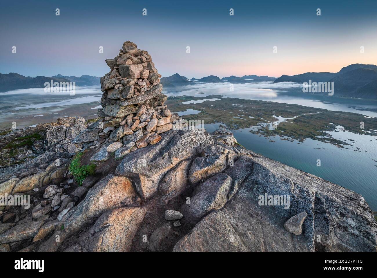 Piramide di pietra in cima a Hoven al crepuscolo, montagne all'orizzonte e fiordi con le nuvole, Gissoy, Lofoten, Nordland, Norvegia Foto Stock