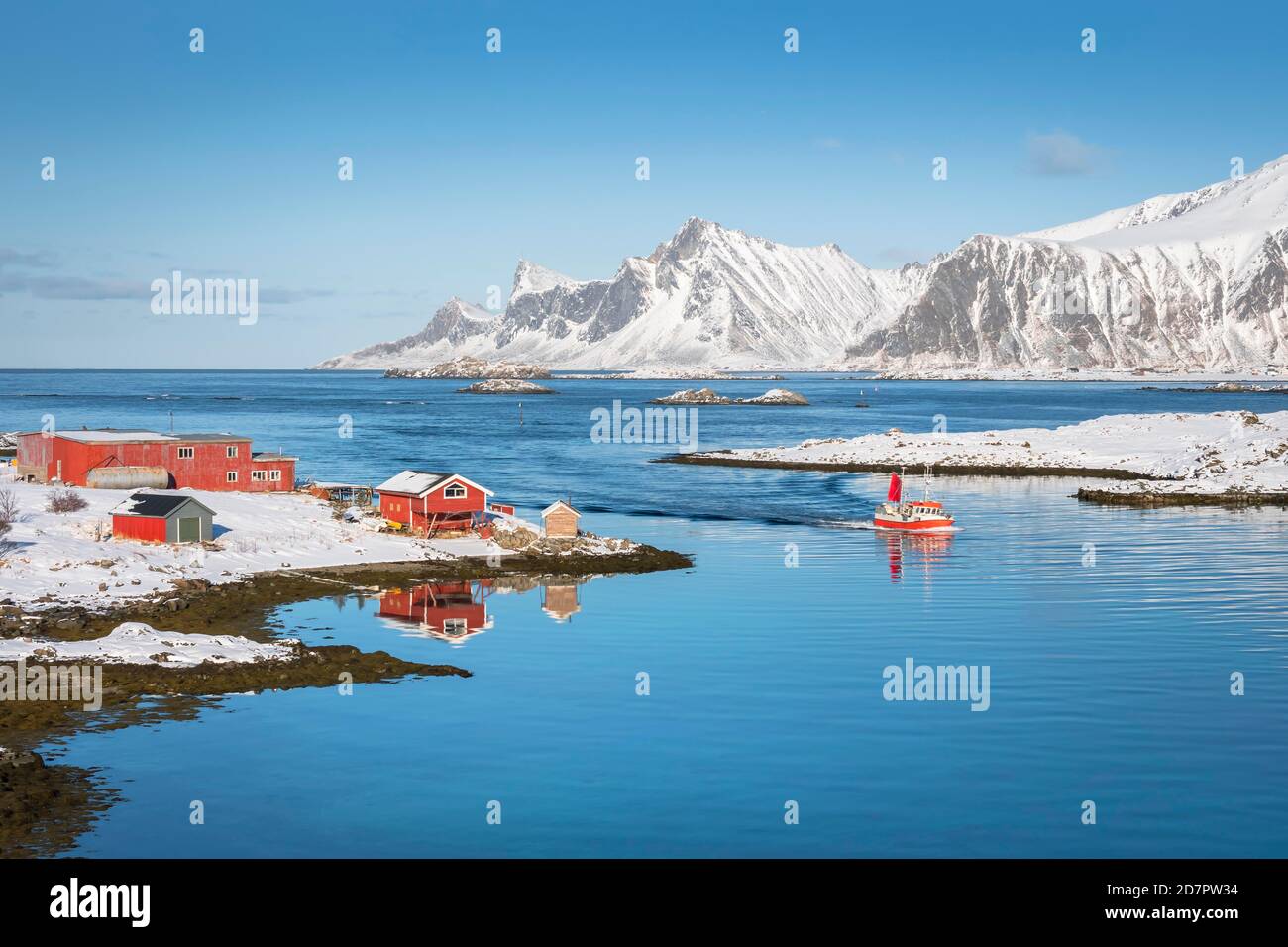 Casa colonica rossa e barca da pesca si riflettono nel fiordo Rossoy Straumen, sullo sfondo l'oceano, le montagne innevate Hustinden e Bjoerntinden Foto Stock