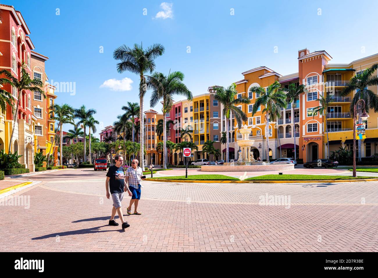 Napoli, USA - 30 aprile 2018: Condomini fronte baia colorati edifici multicolore con fontana d'acqua, persone candite sulla strada e palme Foto Stock