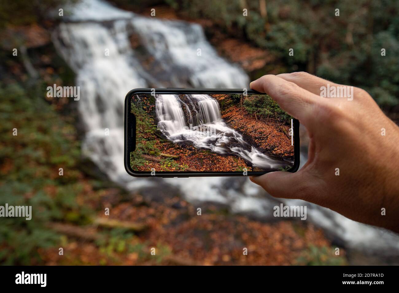 Persona che tiene un telefono cellulare che prende una foto di Merry Falls - DuPont state Recreational Forest - Cedar Mountain, vicino a Brevard, Carolina del Nord, USA [Co Foto Stock