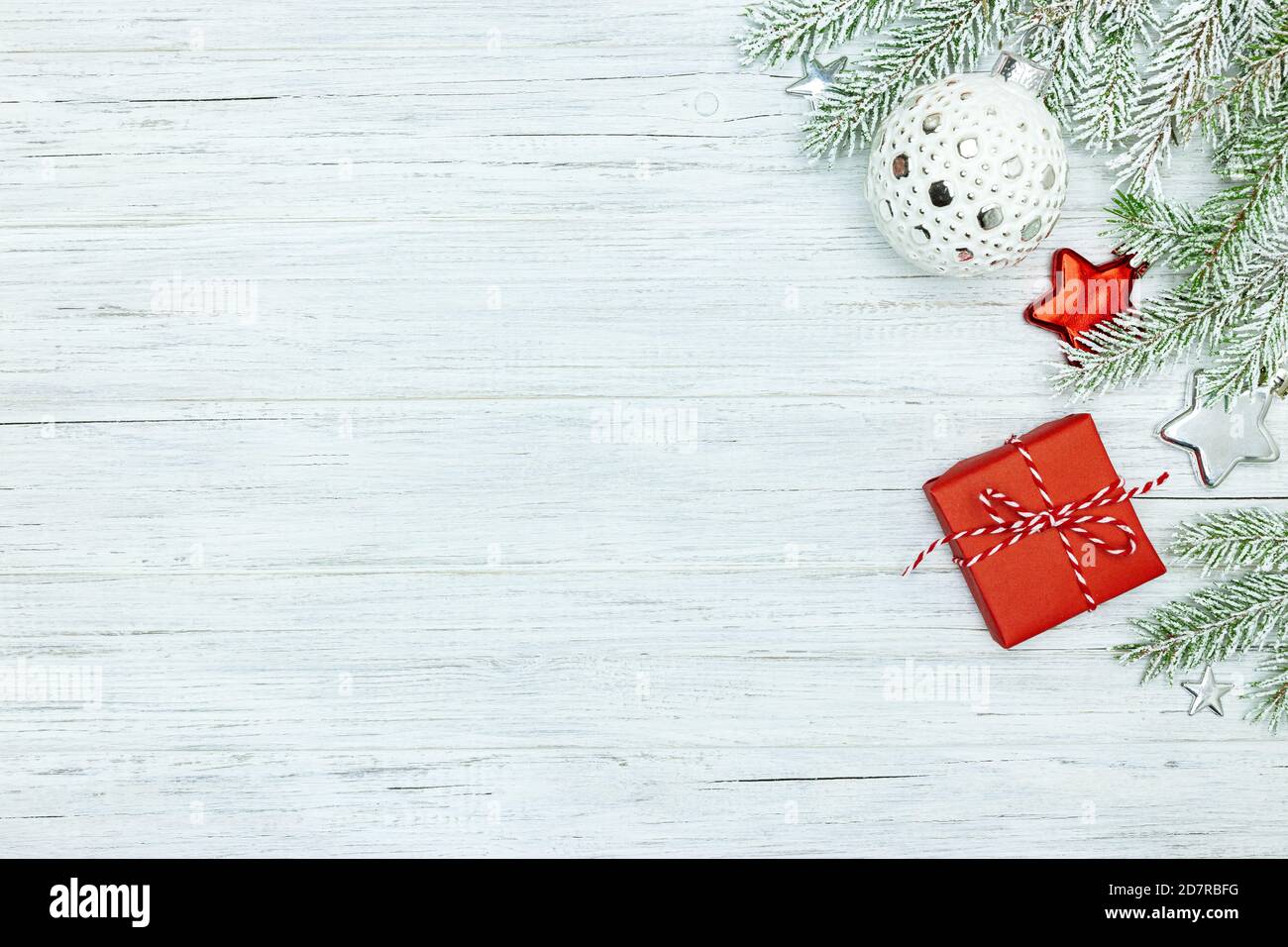 nuovo anno di legno sfondo. albero di natale nevoso ramo, palla di vetro e stelle e piccola scatola regalo rosso Foto Stock