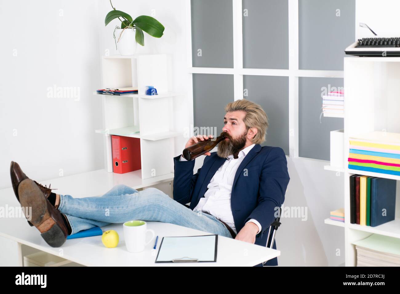 Un uomo d'affari ubriaco annoiato in ufficio alla fine della giornata lavorativa. Uomo d'affari che beve dallo stress. Foto Stock