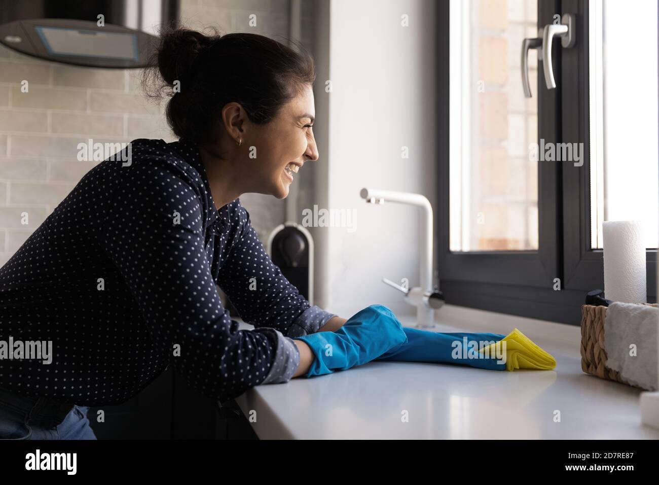 Sorridente donna indiana pulizia contatore cucina con tovagliolo Foto Stock