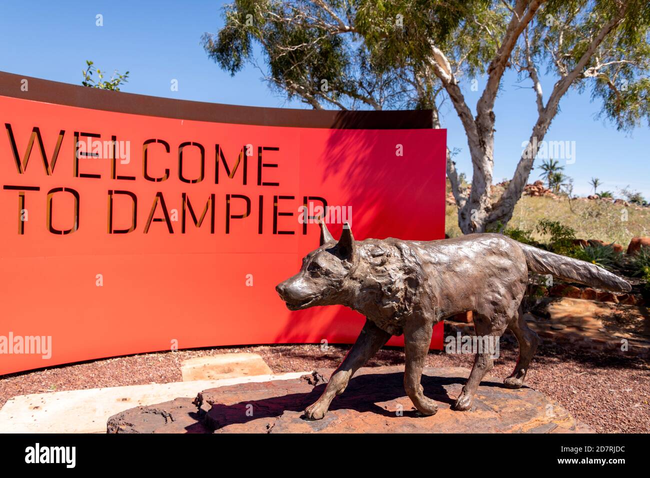 Segno che accoglie la gente a Dampier e una statua del cane rosso. Foto Stock