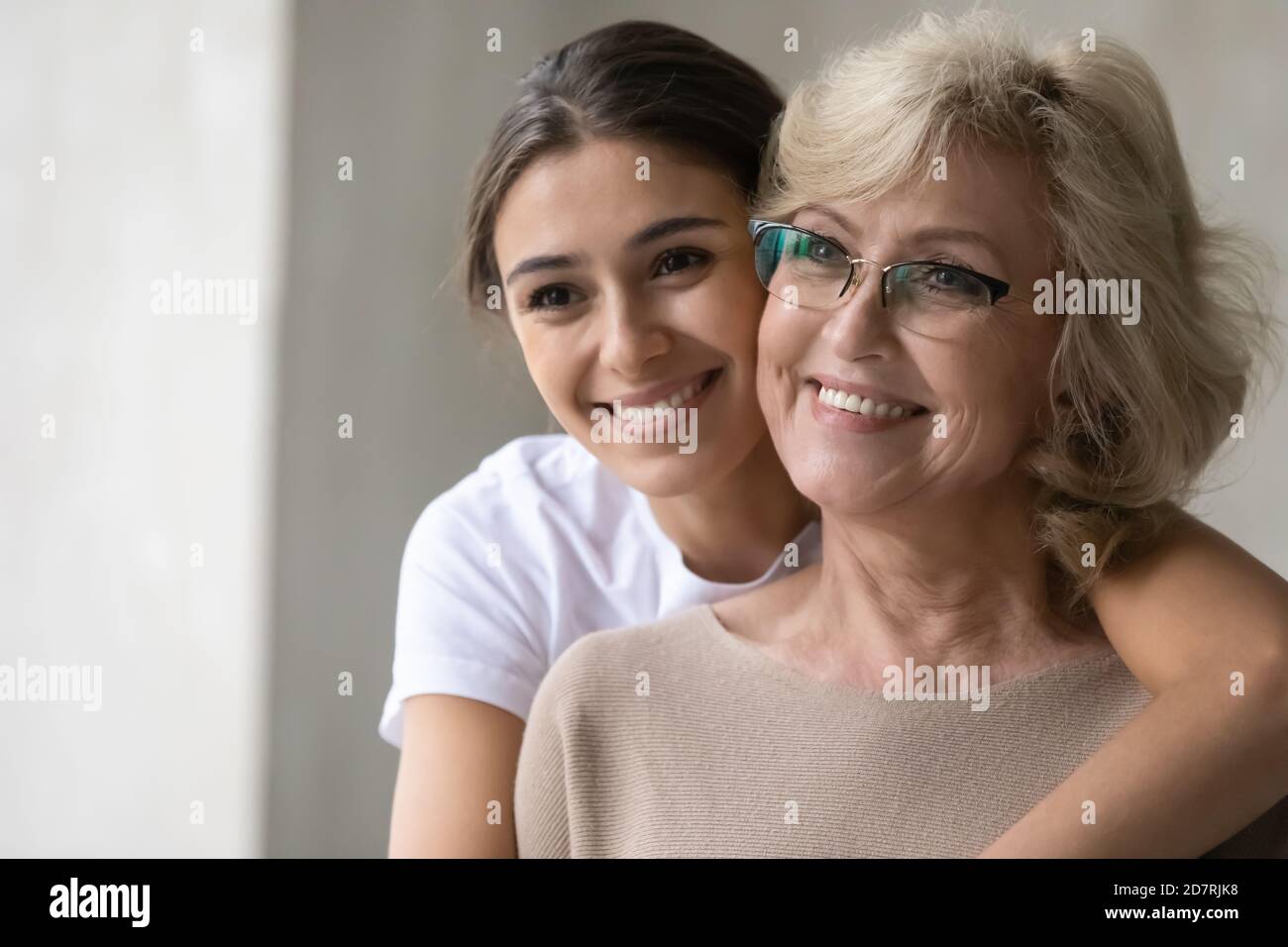 Madre matura sorridente e figlia adulta guardano a distanza sognando Foto Stock