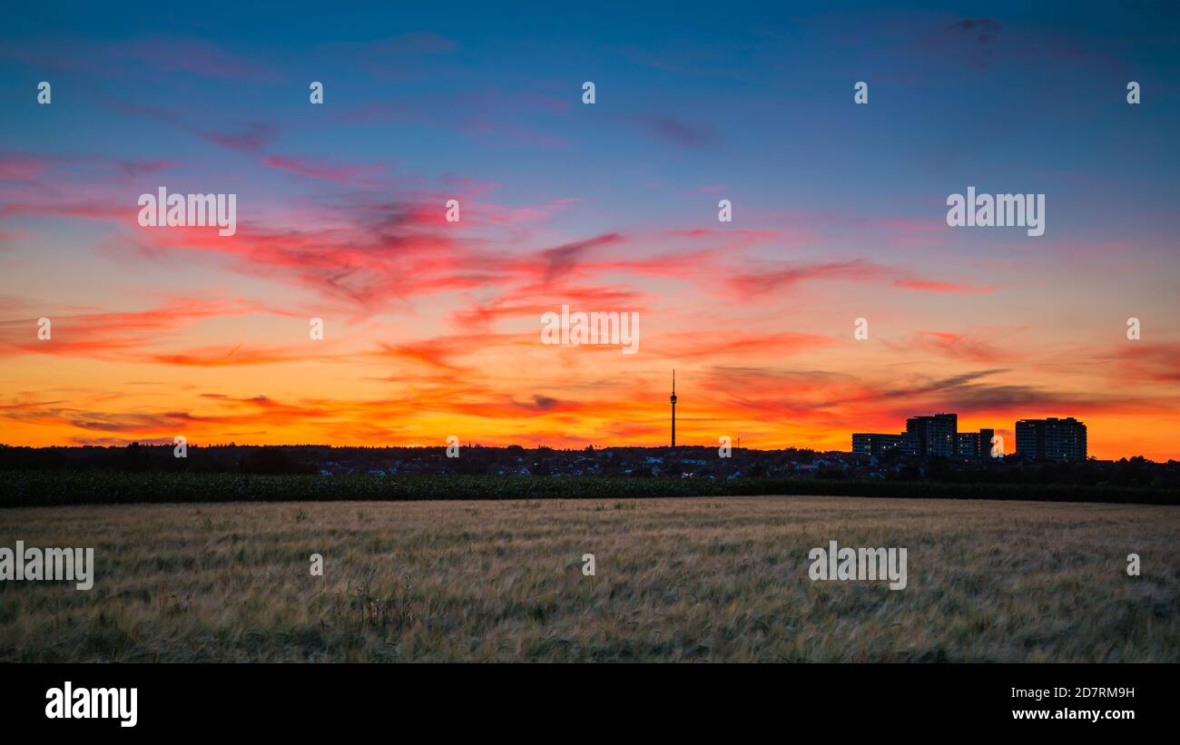 Germania, Stoccarda, il cielo rosso intenso del tramonto sopra i campi e la torre della tv Fernsehturm in estate all'ora blu Foto Stock