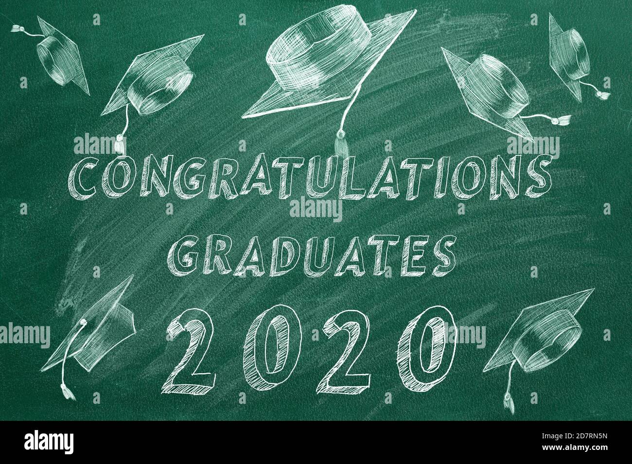 Testo di disegno a mano 'Congratulazioni laureati. 2020.' e tappi graduati sulla lavagna verde. Foto Stock