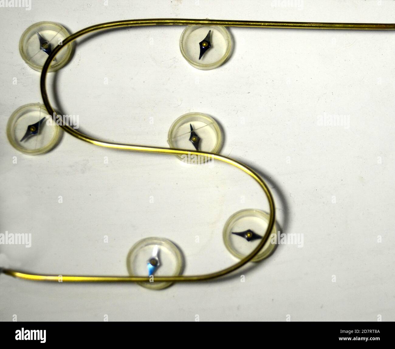 Campo magnetico attorno ad un conduttore. La bussola aghi allineare il campo generato dalla corrente piuttosto che i poli giromagnetico. Nero sul co Foto Stock