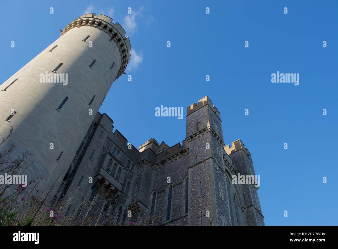 Guardando in su alla torre rotonda e la casa di gatehouse su un castello tradizionale di pietra (inglese / europeo) contro un cielo estivo blu luminoso. La freccia si fenderà nel da a. Foto Stock