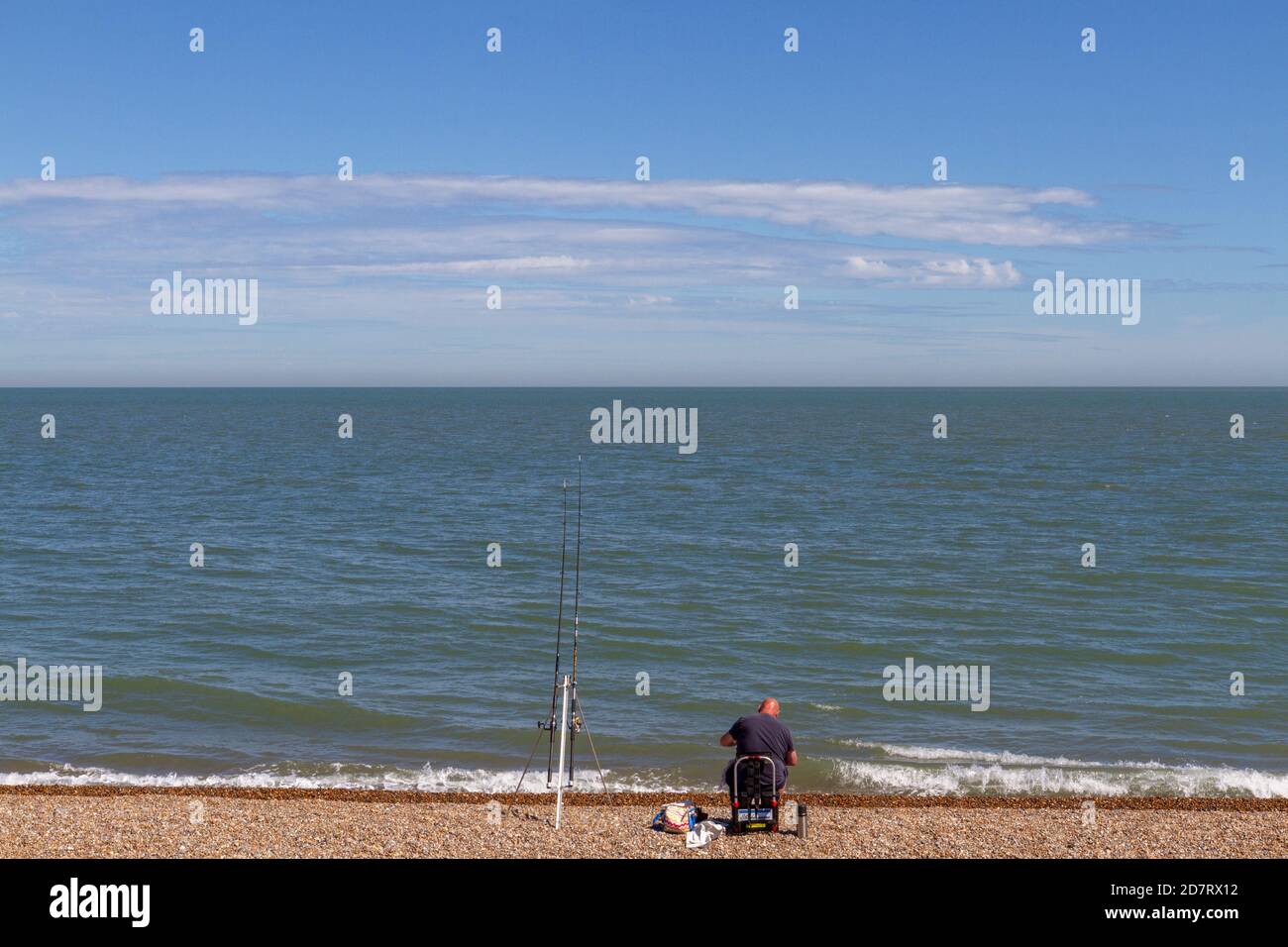 Lone uomo seduto sulla spiaggia di pesca (o surf pesca), Aldeburgh, Woodbridge, Suffolk, UK. Foto Stock