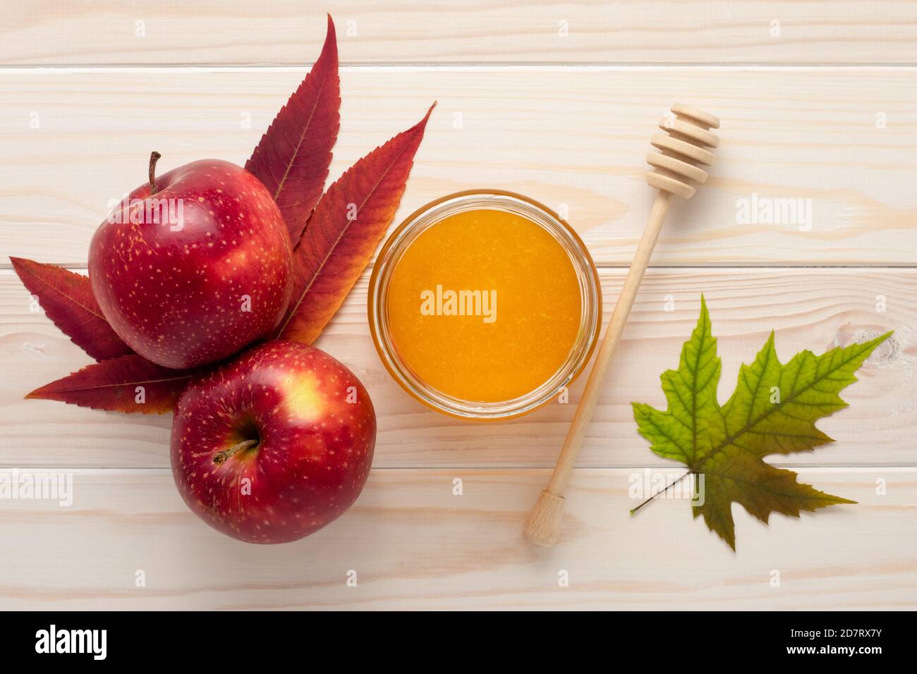 Miele in un vaso di vetro e mele rosse su sfondo bianco di legno. Celebrazione Rosh Hashanah, un anno pieno di beatitudine. Stagione autunnale, foglie autunnali. Raccolto conc Foto Stock
