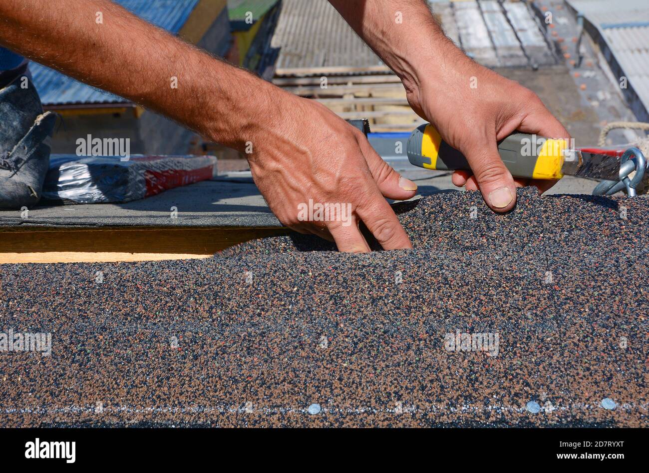 Riparazione del tetto mediante taglio di feltro o di tegole bituminose durante lavori di impermeabilizzazione. Foto Stock