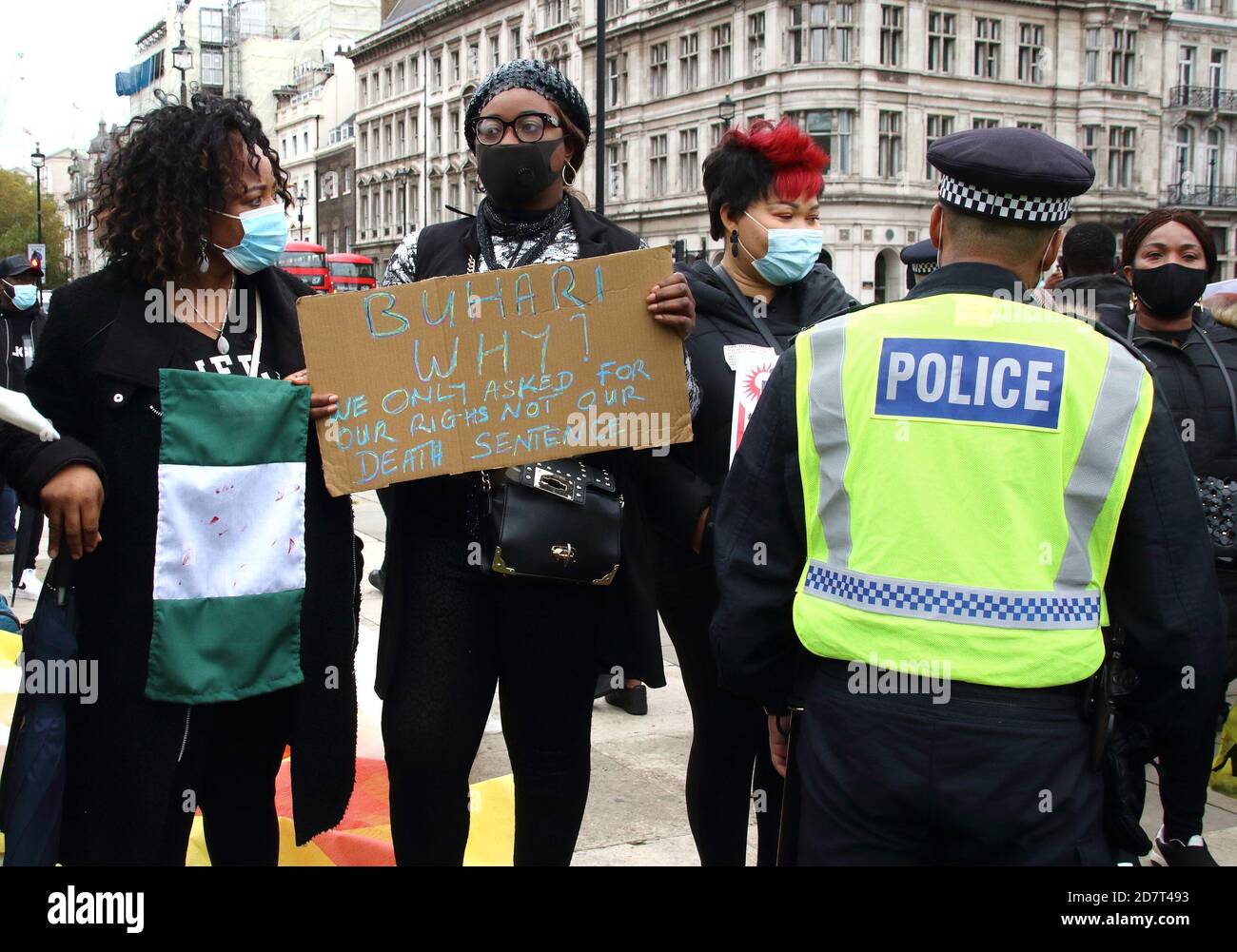 I manifestanti con maschere che tengono cartelli interagiscono con la polizia durante la protesta. I nigeriani con sede a Londra protestano in Piazza del Parlamento contro la brutalità della squadra speciale anti-rapina (SARS) della polizia nigeriana. Amnesty International ha confermato di aver avuto prove di un uso eccessivo della forza, causando la morte di alcuni manifestanti al casello di Lekki martedì scorso. Il Presidente Buhari ha sciolto la SARS il 11 ottobre, ma questi manifestanti hanno ancora chiesto le sue dimissioni. Foto Stock