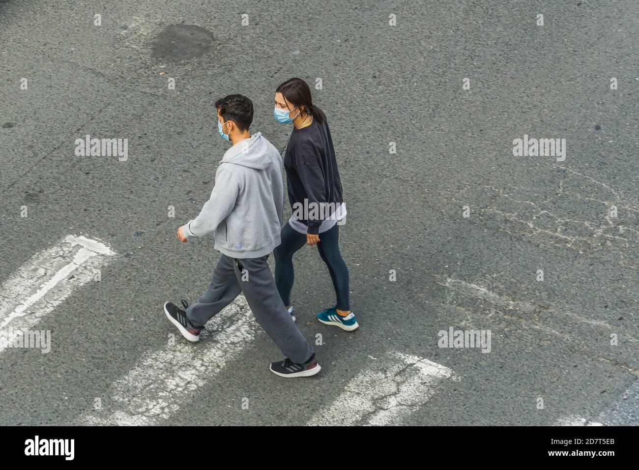 Persone con covid-19 maschere all'aperto. Una coppia non identificata con protezione del viso cammina su una traversata di zebra a Salonicco, in Grecia. Foto Stock