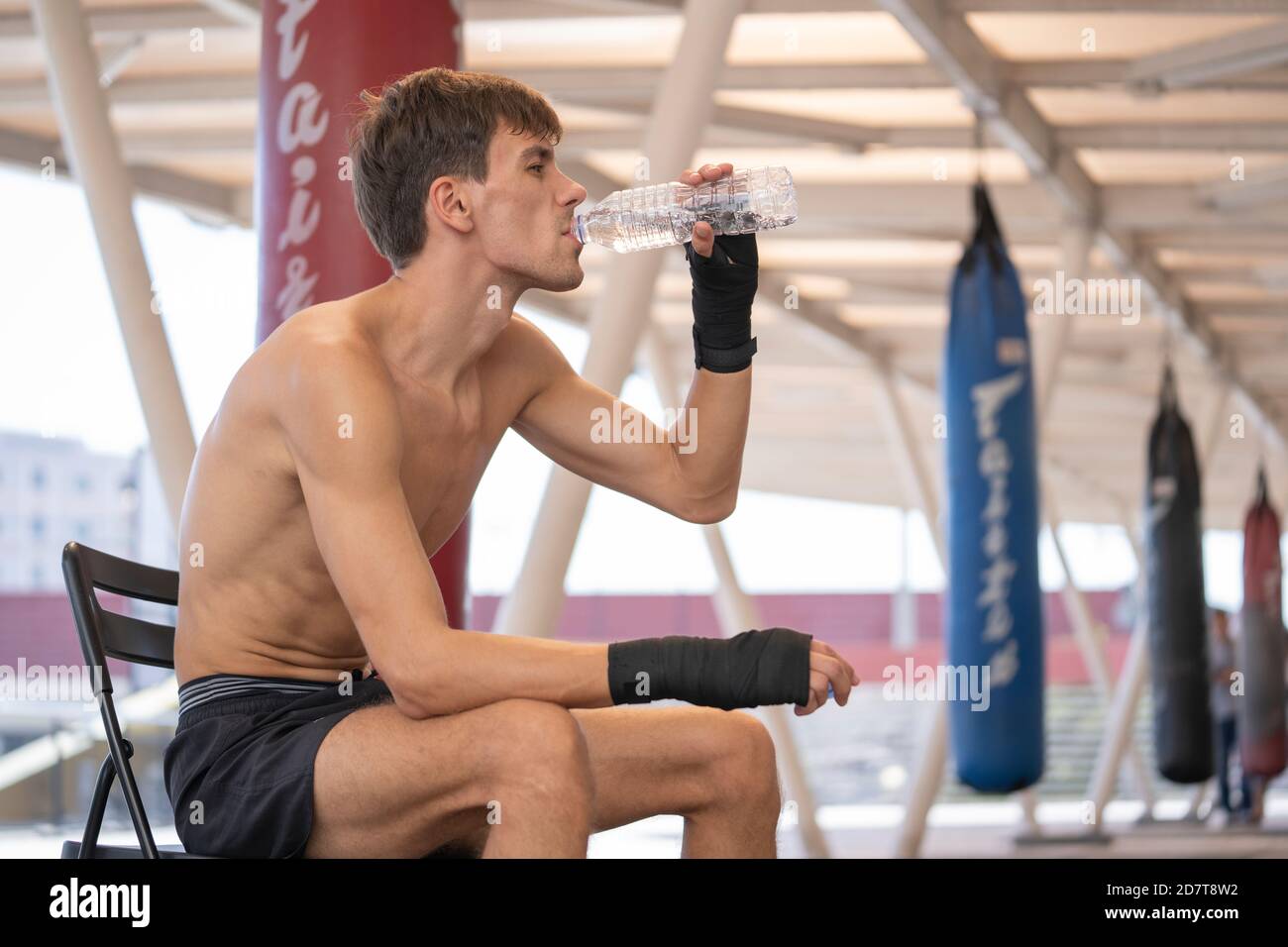 Uomo acqua potabile dopo aver praticato muay thai in palestra. Foto Stock