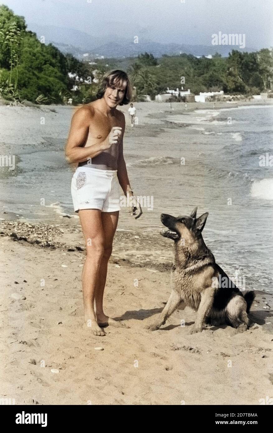 James Hunt, britischer Autorennfahrer, mit seinem Hund am Strand, um 1974. British car racing driver James Hunt con il suo cane sulla spiaggia, intorno al 1974. Foto Stock