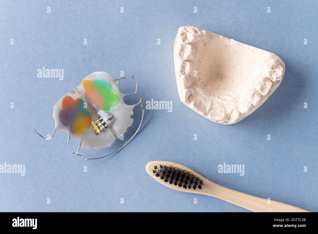piastra dentale, calco in gesso della mascella del bambino e spazzolino da denti su sfondo blu. Salute dentale Foto Stock