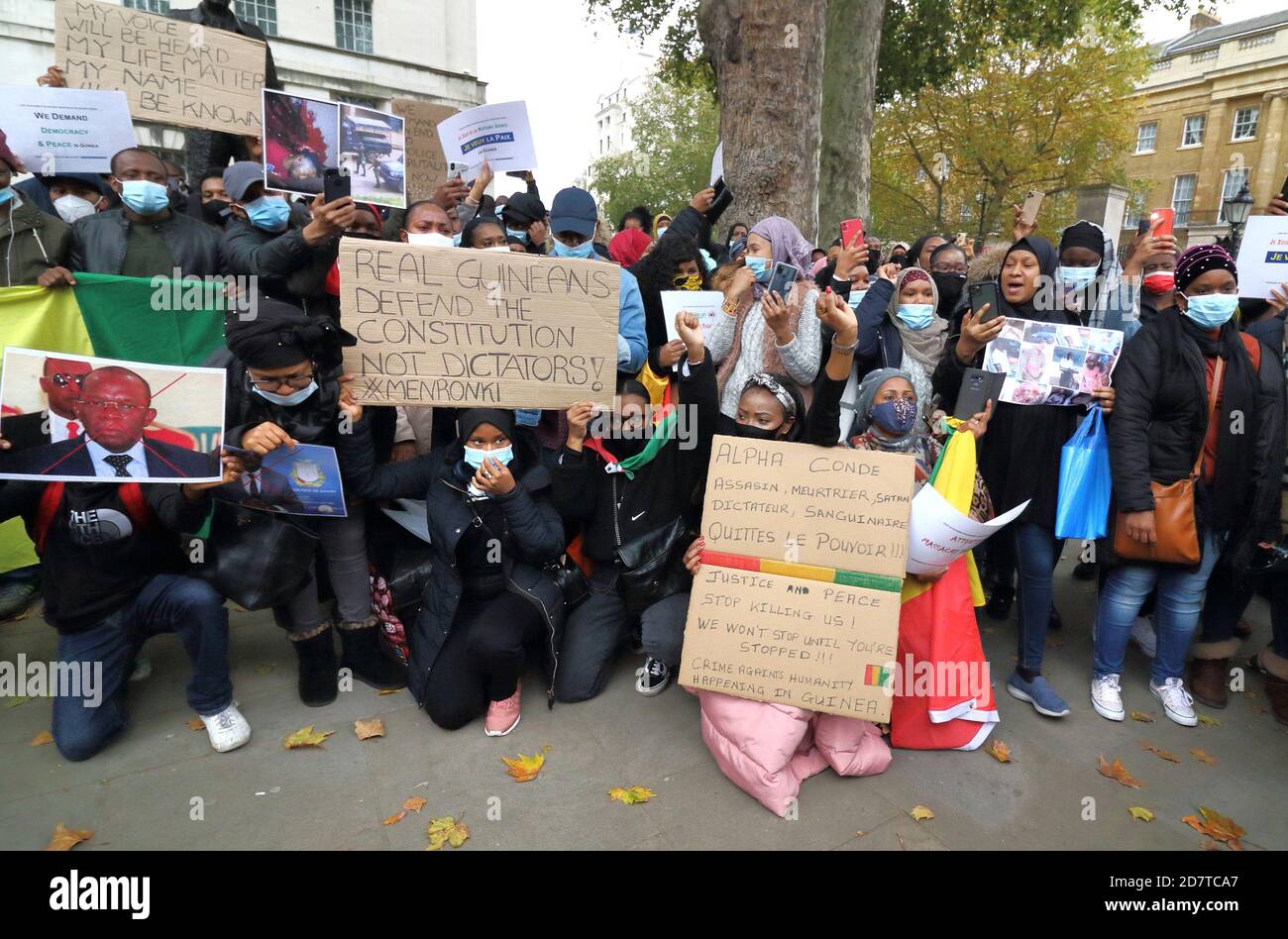 I manifestanti che indossano maschere tengono in mano cartelli e ritratti delle vittime dichiarate del regime durante il rally.Guineani nel Regno Unito protestano fuori Downing Street dopo che il presidente della Guinea Alpha Conde è stato rieletto con le rivendicazioni dell'opposizione che l'elezione è stata rigata. Foto Stock