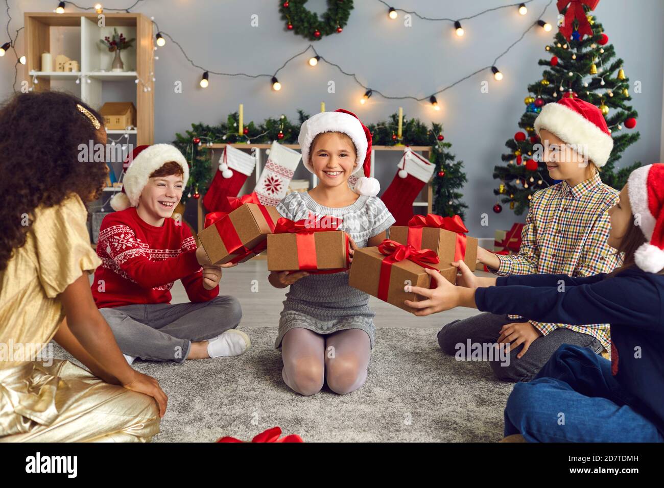 Felice sorridente bambina ottenere un sacco di regali per Natale dai suoi amici o fratelli Foto Stock